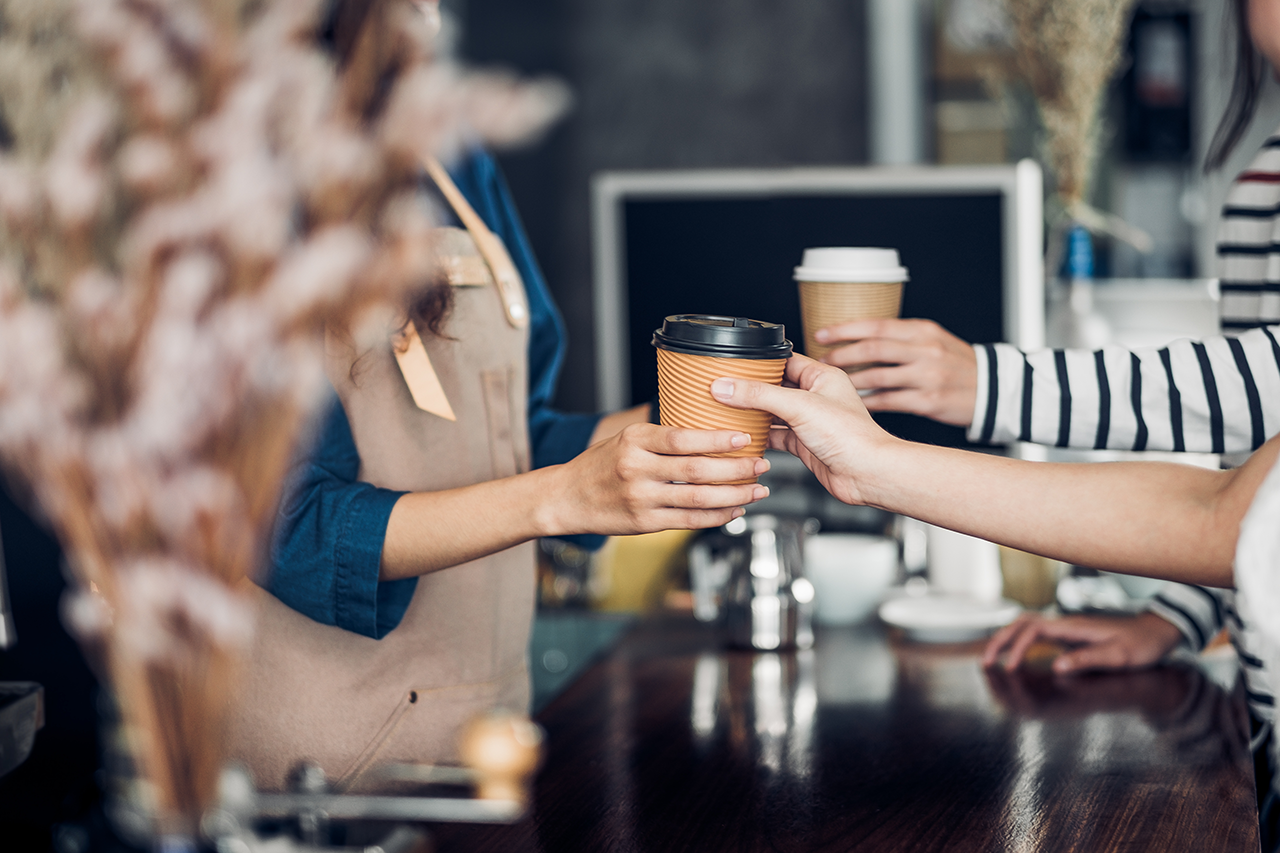 Barista-served-take-away-hot-coffee-cup-to-customer-at-counter-bar-in-cafe-restaurant